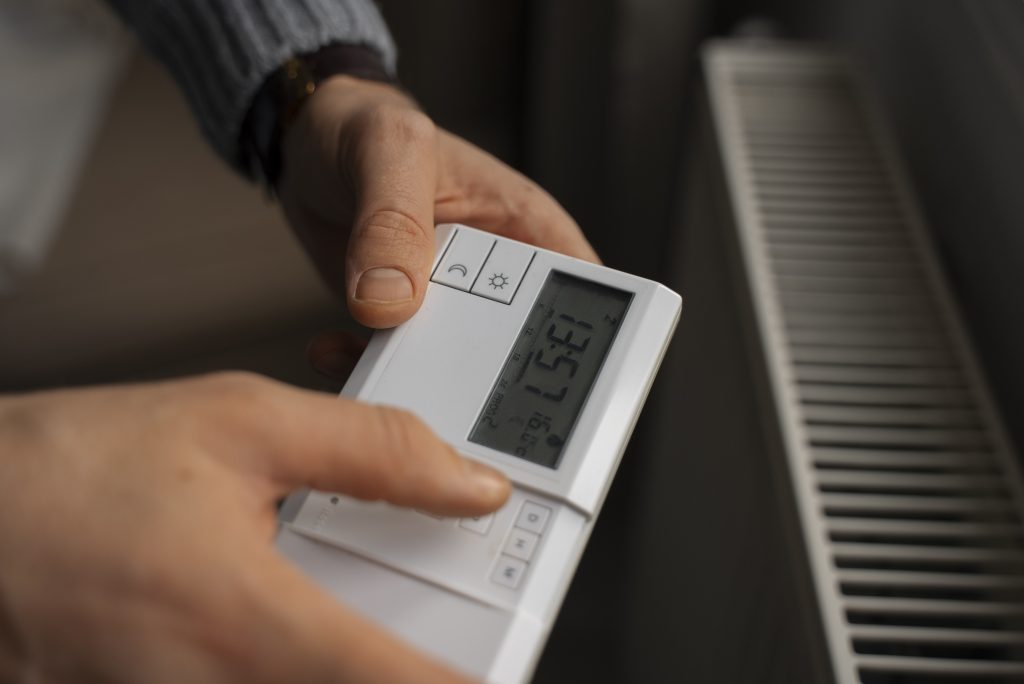 man-turning-off-thermostat-during-energy-crisis